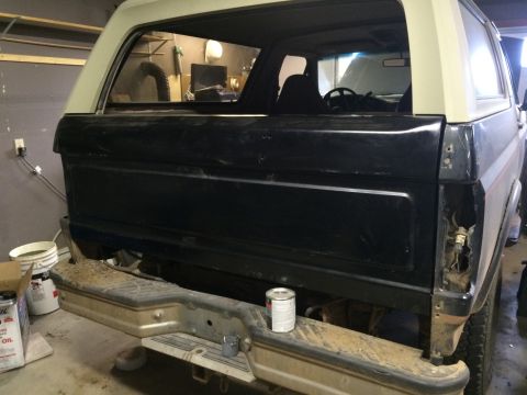 2004 Ford F-250 - The rear passenger side of a dark blue SUV, possibly a Ford Bronco, is shown in a garage setting. The tailgate panel is painted black, and…