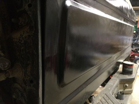 2004 Ford F-250 - A close-up side view of the lower body panel of a dark-colored truck, possibly a Ford F-250, showing a textured finish and a can of paint o…