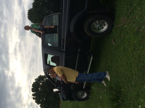 2004 Ford F-250 - A young boy sits on the open window frame of a black Ford F-250 pickup truck while an adult man holds a child near the driver's side door.…