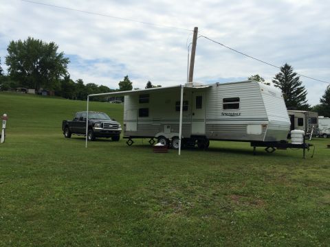 2004 Ford F-250 - A black Ford F-250 pickup truck is parked on a grassy campsite next to a white Springdale travel trailer with its awning extended. The truc…