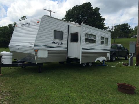 2004 Ford F-250 - A white and gray Springdale travel trailer is parked on a grassy area, connected to a dark gray Ford F-250 pickup truck. The truck is parke…