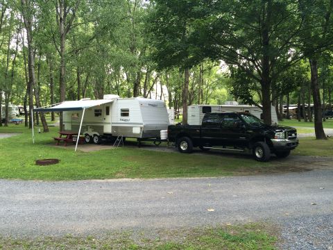 2004 Ford F-250 - A black Ford F-250 pickup truck is parked next to a travel trailer at a campsite. The truck is facing right, and the trailer is connected t…