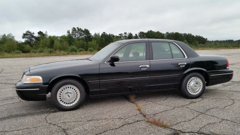 2001 Ford Crown Victoria - Photograph of a black Ford Crown Victoria sedan in profile, not a technical document.