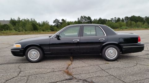 2001 Ford Crown Victoria - Photograph of a black Ford Crown Victoria sedan in profile, not a technical document.