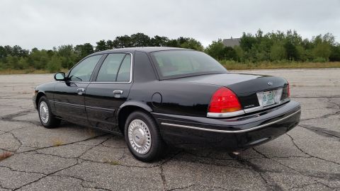 2001 Ford Crown Victoria - Photograph of a black Ford Crown Victoria sedan from the rear, not a technical document.