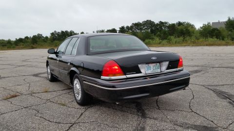 2001 Ford Crown Victoria - Photograph of a black Ford Crown Victoria sedan from the rear, not a technical document.