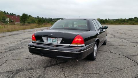 2001 Ford Crown Victoria - Photograph of a black Ford Crown Victoria sedan from the rear three-quarter, not a technical document.