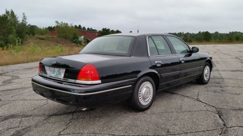 2001 Ford Crown Victoria - A black 2001 Ford Crown Victoria is viewed from the rear, with a distinctive multi-colored stripe across its trunk.