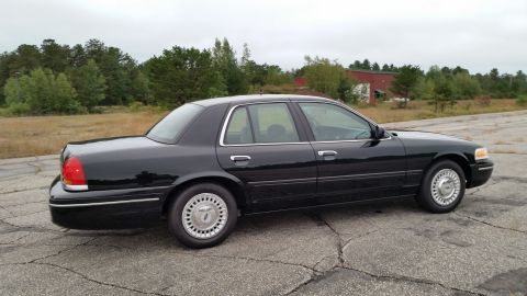 2001 Ford Crown Victoria - Side view of a dark blue 2001 Ford Crown Victoria sedan parked on asphalt.