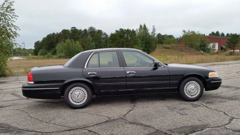 2001 Ford Crown Victoria - A black 2001 Ford Crown Victoria is parked outdoors on a cloudy day.