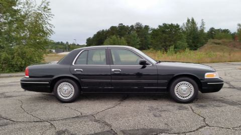 2001 Ford Crown Victoria - Side view of a dark 2001 Ford Crown Victoria sedan parked outdoors.