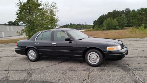 2001 Ford Crown Victoria - A black 2001 Ford Crown Victoria is parked outdoors on a cloudy day.