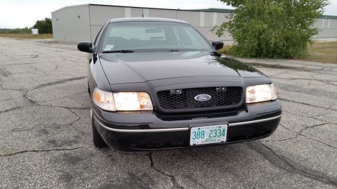 2001 Ford Crown Victoria - This black 2001 Ford Crown Victoria is shown from the front, its distinctive grille and headlights.