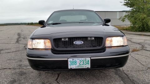 2001 Ford Crown Victoria - Front view of a black 2001 Ford Crown Victoria parked on asphalt, with a clear sky overhead.