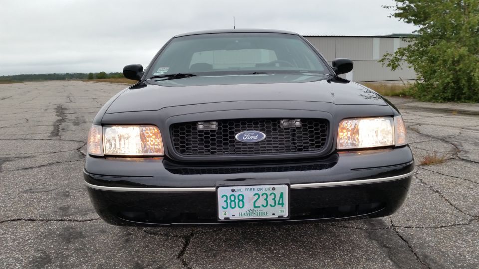 2001 Ford Crown Victoria front view with headlights on, showing grille and New Hampshire license plate