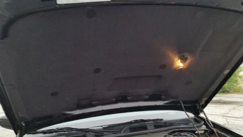 2001 Ford Crown Victoria - The underside of a car's hood is visible, along with a small interior light and part of the engine compartment.