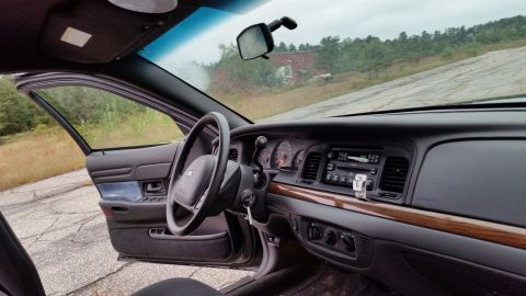 2001 Ford Crown Victoria - Interior view of a 2001 Ford Crown Victoria with the driver's door open, showing the dashboard and steering wheel.