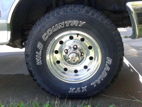 1996 Ford Bronco - A close-up view of a vehicle's wheel and tire, chrome accents and prominent tire branding.