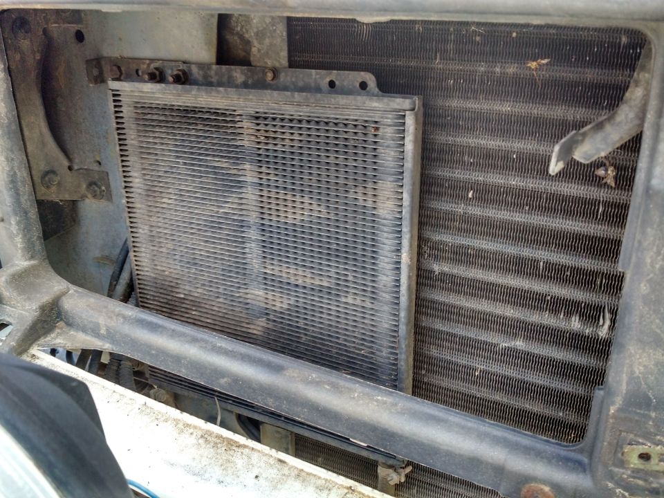 Transmission cooler mounted in front of radiator, showing fins and mounting brackets