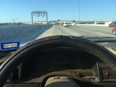 1993 Ford Bronco - View from the driver's seat of a vehicle on a highway, with a Texas license plate visible on the dashboard.