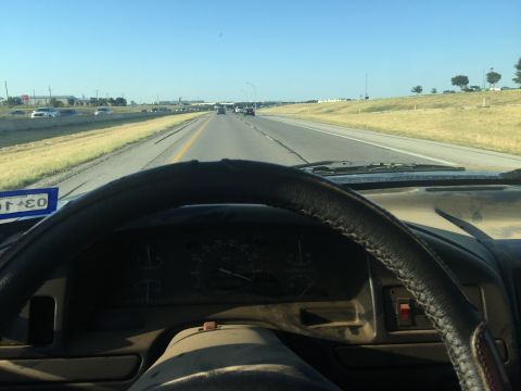 1993 Ford Bronco - Driving on a highway with other vehicles visible in the distance under a clear blue sky.
