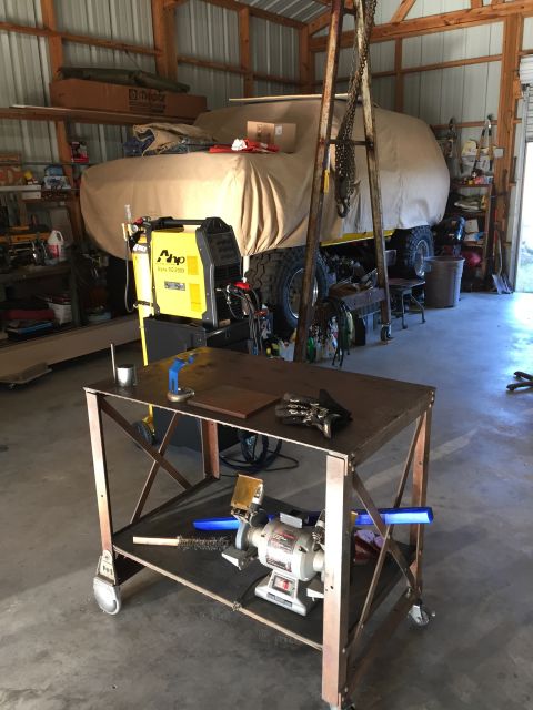 1978 Ford Bronco - A vehicle covered by a tarp sits in a garage, surrounded by tools and equipment.