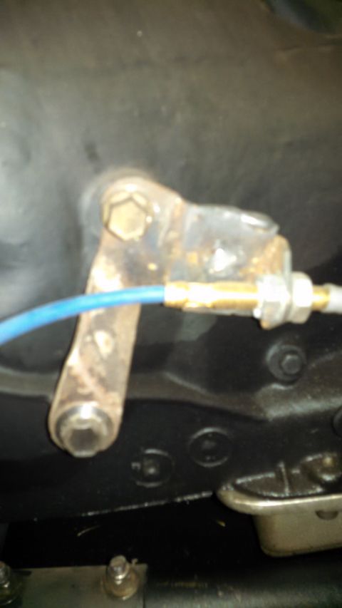 1967 Ford F-250 - A close-up view of a rusty metal bracket with a blue wire connected to it, likely part of a vehicle's mechanical system.