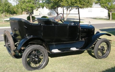 1923 Ford Model T - A vintage black touring car sits on a grassy lawn, its open-top design and spoked wheels indicative of early automotive history.