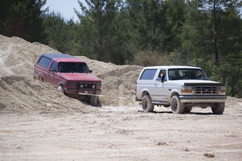 1995 Ford Bronco - White 1995 Ford Bronco tows a red Bronco out of a sandy ditch.