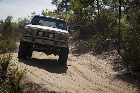 1995 Ford Bronco - This 1995 Ford Bronco navigates a sandy off-road path surrounded by desert vegetation.