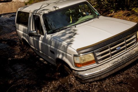 1995 Ford Bronco - White 1995 Ford Bronco navigates a muddy off-road trail.