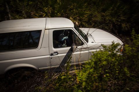 1995 Ford Bronco - 1995 Ford Bronco navigating a muddy, overgrown trail.