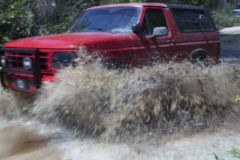 1995 Ford Bronco - 1995 Ford Bronco navigating a water crossing with significant splash.