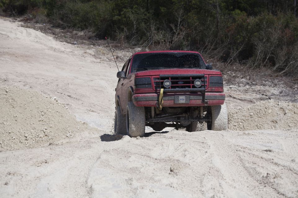 1995 Ford Bronco driving on a sandy, off-road trail