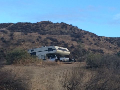 1997 Dodge 3500 - A 1997 Dodge 3500 pickup truck is outfitted with a camper shell and parked in a dry, hilly landscape.