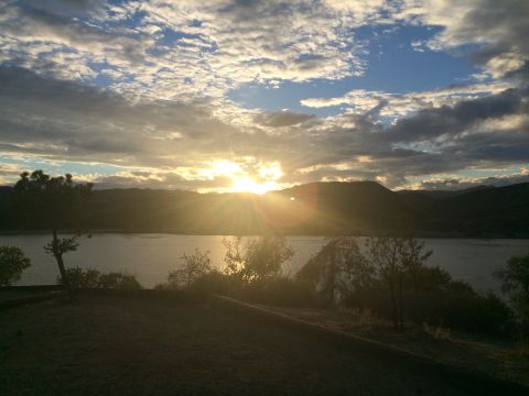 1997 Dodge 3500 - A beautiful sunset casts rays of light over a tranquil lake and surrounding hills.