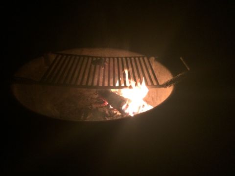 1997 Dodge 3500 - A fire pit glows with flames and a grill grate is positioned above the burning wood.