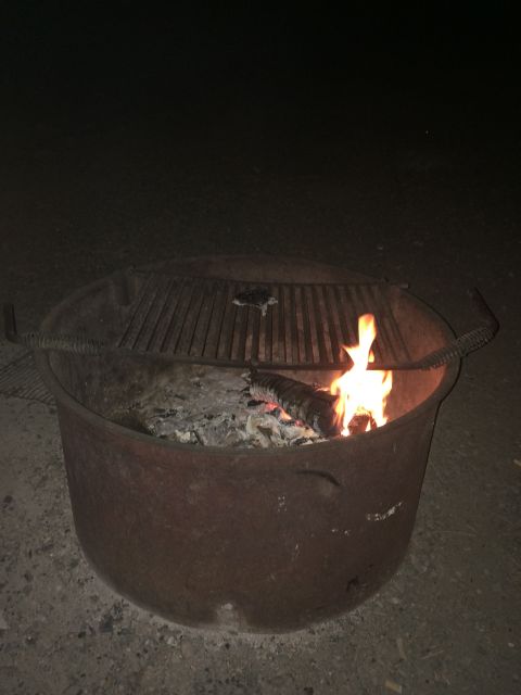1997 Dodge 3500 - A fire pit glows with burning logs and embers, topped with a metal grill.