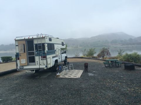1997 Dodge 3500 - A motorhome is parked at a campsite with a lake and hills in the background.