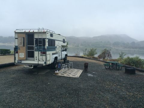 1997 Dodge 3500 - A 1997 Dodge 3500 camper truck is parked at a campsite next to a lake on a foggy morning.