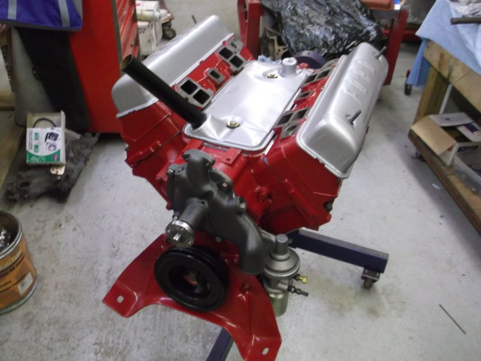 Red V8 engine with silver valve covers on a red engine stand