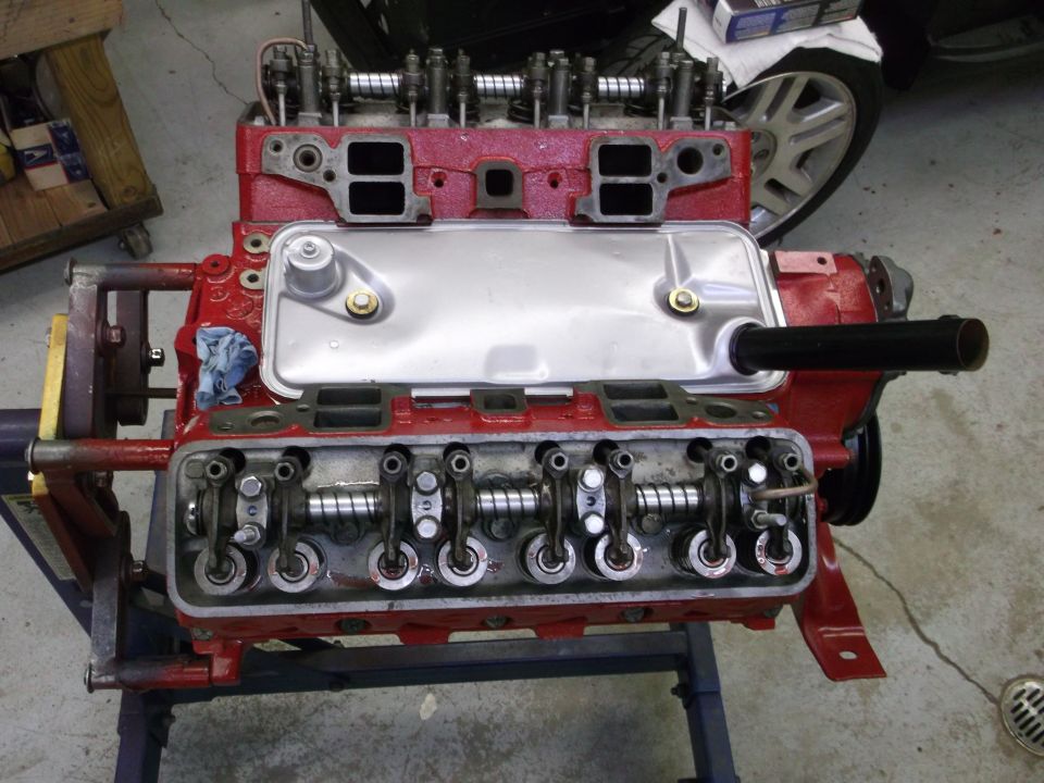 Red V8 engine block with exposed valves and rocker arms on stand