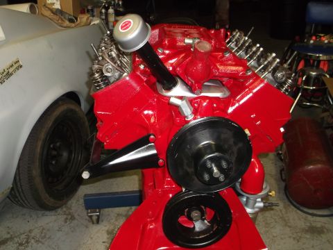 1957 Ford Custom Sedan - A freshly painted V8 engine sits next to a car in a garage.