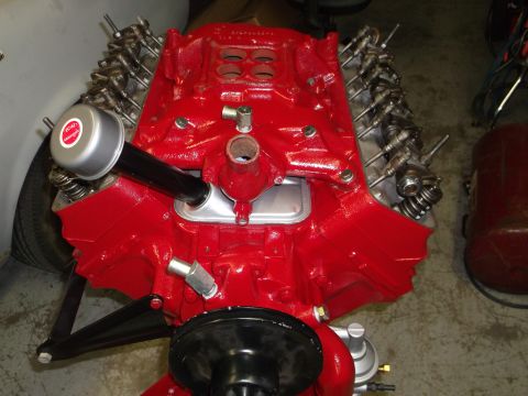 1957 Ford Custom Sedan - Engine detail shot, likely from a 1957 Ford Custom Sedan, a red V8 engine with a prominent air cleaner and visible valve train components.