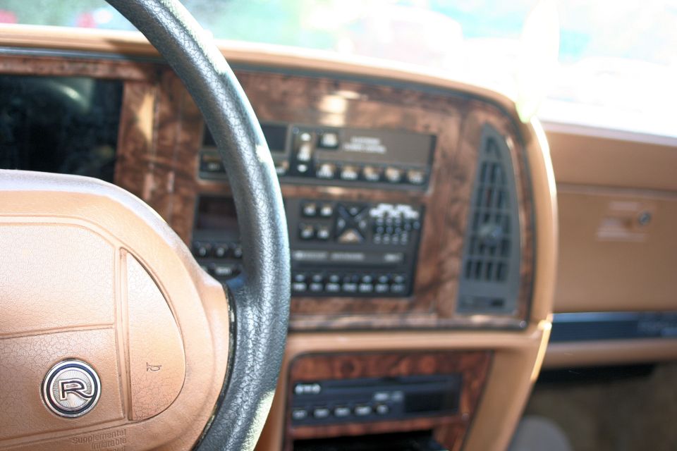 1991 Buick Reatta interior showing woodgrain dashboard, radio, and steering wheel with R logo