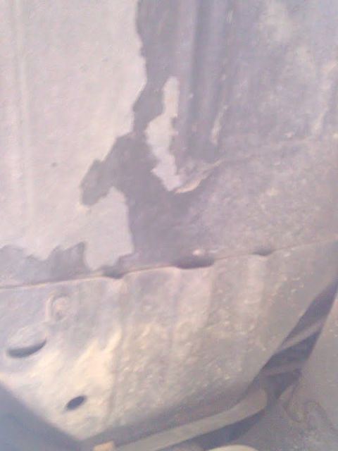 1978 Ford Bronco - Close-up of a heavily rusted metal panel with visible holes and a torn section.