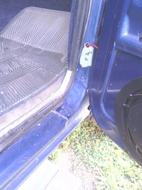 1978 Ford Bronco - Close-up view of a vehicle's interior door jamb area, showing a floor mat and a hanging tag.