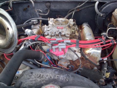 1978 Ford Bronco - Close-up view of a vehicle's engine bay, a carburetor and red spark plug wires.