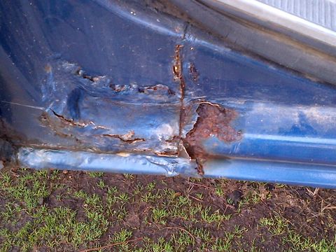1978 Ford Bronco - The lower edge of a vehicle's door shows extensive rust and corrosion, indicating structural damage.