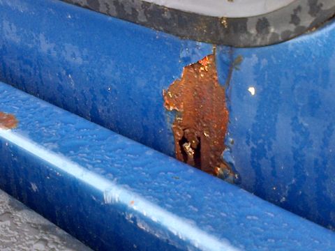 1978 Ford Bronco - Close-up of rusted blue metal, likely a vehicle part, showing decay.